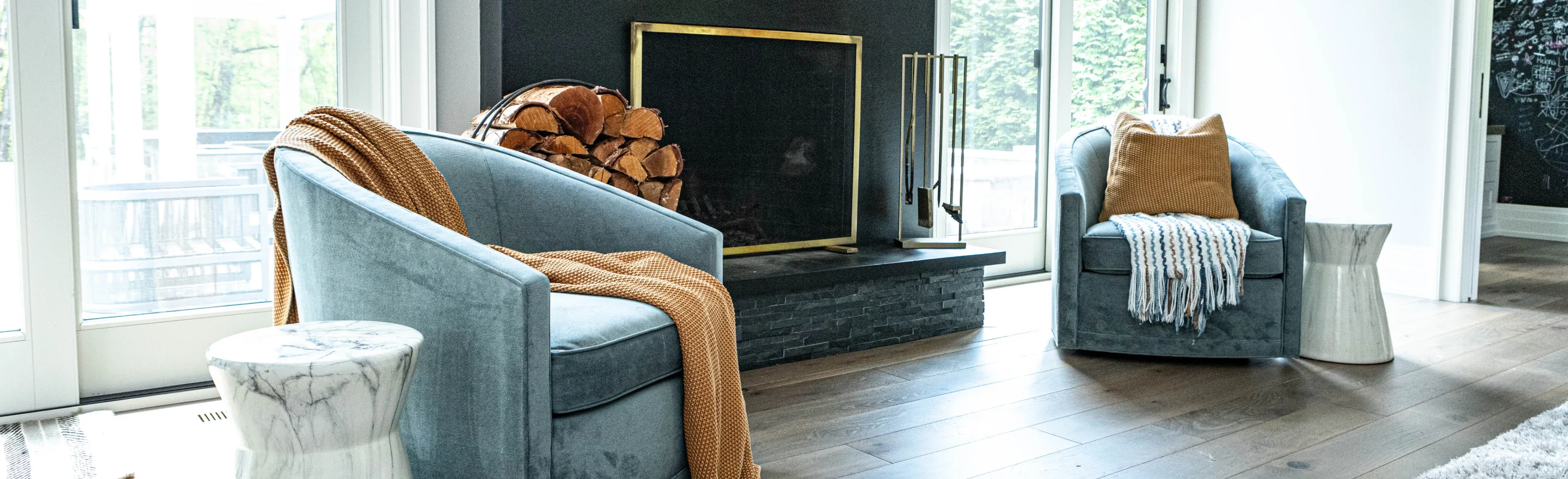 Living room with blue velvet swivel chairs and a rust throw in front of a black stone fireplace